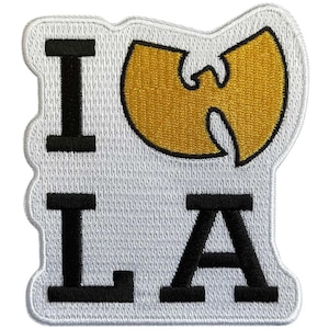 May include: Embroidered patch with the text "I LA" in black block letters, with a gold emblem in the shape of a bat. The patch has a white background and a white border.
