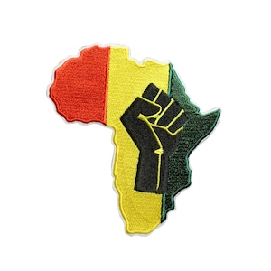 May include: An embroidered patch in the shape of the African continent featuring vertical stripes of red, yellow, and green. A black raised fist silhouette is centered over the yellow and green sections, with a white border outlining the entire shape.