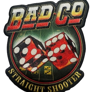 May include: Embroidered patch with the text "BAD CO" in a bold, stylized font. The patch features two red dice with white dots, set against a green background. The words "STRAIGHT SHOOTER" are arched below the dice.