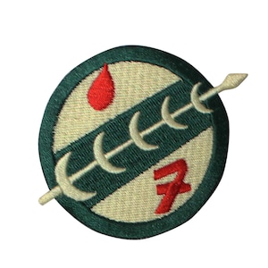 May include: Embroidered patch featuring a circular design with a green border. The patch includes a red teardrop shape, a white spear, and a series of white crescent shapes. A red number 7 is also present. The background is beige and green.