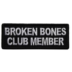 May include: Black rectangular patch with white embroidered text that reads "BROKEN BONES CLUB MEMBER". The patch has a black border and is likely designed to be sewn or ironed onto clothing or accessories.
