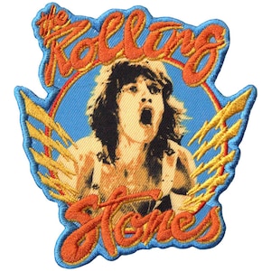 May include: Embroidered patch featuring a portrait of a person with an open mouth, surrounded by the words "The Rolling Stones" in orange script. The design includes a blue background, a rainbow, and yellow lightning bolts.