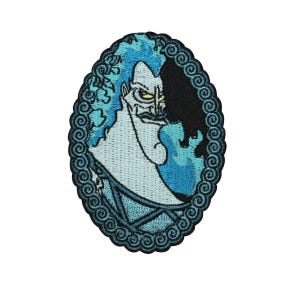 May include: Oval-shaped embroidered patch featuring a stylized illustration of Hades from Disney's Hercules. The design showcases Hades with blue flames and hair, set against a black background. The patch is bordered with a decorative blue swirl pattern.