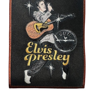 May include: Embroidered patch featuring Elvis Presley playing a guitar and singing into a microphone. The patch has a black background with gold text that reads "Elvis Presley". The patch has a brown border and a Sun Records logo.