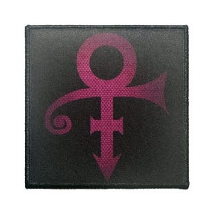 May include: A square, black patch featuring a magenta symbol. The symbol is a combination of the male and female symbols, with a teardrop shape at the bottom. The patch has a stitched border.
