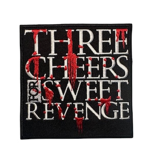 May include: A black square patch with white text that reads "THREE CHEERS FOR SWEET REVENGE" with red dripping accents. The patch is likely for a jacket or bag.