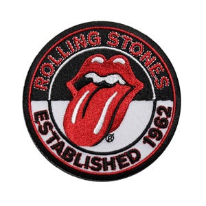May include: Round embroidered patch featuring the Rolling Stones' iconic red lips and tongue logo. The patch has a black border with the words "ROLLING STONES" and "ESTABLISHED 1962" in white lettering.