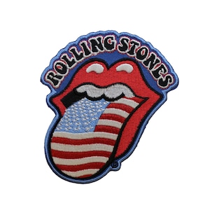 May include: A Rolling Stones patch featuring the iconic red lips and tongue logo with an American flag design on the tongue. The logo is outlined in blue with the words "Rolling Stones" in black.