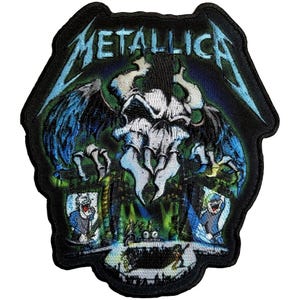 May include: Embroidered patch featuring the band name "METALLICA" in blue, above a skull with wings and a detailed background. The patch has a black border and is suitable for jackets or bags.