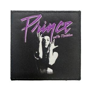 May include: A black square patch featuring a purple embroidered design with the name "Prince" and the text "and the Revolution." The patch includes a black and white image of Prince.