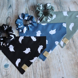 Op de afbeelding: Vier hondenbandanas met een spookpatroon. De bandanas zijn in zwart, blauw, groen en lichtblauw. Elke bandana heeft een klein label met de tekst "Paddy & Maisie's Gear".