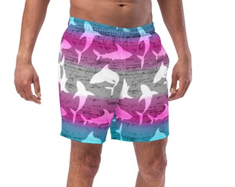 Puede incluir: Un bañador azul, rosa y gris con un estampado de tiburones blancos. Los tiburones están en silueta sobre un fondo degradado.