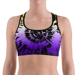 Puede incluir: Un sujetador deportivo negro con un patrón tie-dye en tonos amarillos, morados y blancos. El sujetador tiene un estilo de espalda de nadador y está hecho de una tela elástica y transpirable.