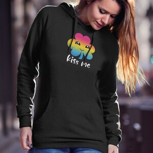 Pu&ograve; includere: Felpa con cappuccio nera con un trifoglio arcobaleno e la scritta "Kiss Me" stampata sul davanti.