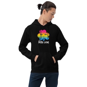 Pu&ograve; includere: Felpa con cappuccio nera con un trifoglio arcobaleno e il testo "kiss me" in bianco.
