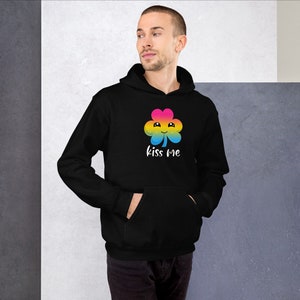 Pu&ograve; includere: Felpa con cappuccio nera con un trifoglio arcobaleno e la scritta "kiss me" stampata sul davanti.