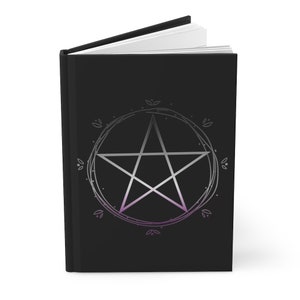 Puede incluir: Un diario negro con un pent&aacute;culo plateado rodeado de un c&iacute;rculo de hojas. El pent&aacute;culo es una estrella de cinco puntas con un degradado de morado y blanco.