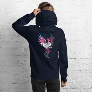 May include: Navy blue hoodie with a colorful phoenix design on the back. The phoenix is depicted in shades of pink, white, blue, and purple. The hoodie has a hood and a relaxed fit.