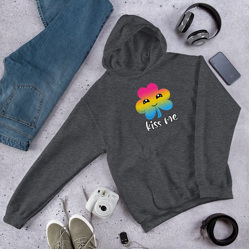 Pu&ograve; includere: Una felpa con cappuccio grigio scuro con un trifoglio arcobaleno e la scritta "Kiss Me" stampata sul davanti.