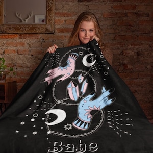 Könnte beinhalten: Schwarze Fleece-Decke mit einem weißen Design aus zwei Händen, die Kristalle und Monde halten. Der Text "Babe" befindet sich am unteren Rand des Designs.