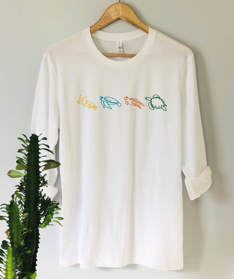 May include: A white long-sleeved t-shirt with a line of four colorful sea turtles embroidered on the front.