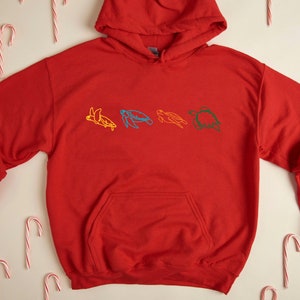May include: Red hooded sweatshirt with a line drawing of five colorful sea turtles on the front.