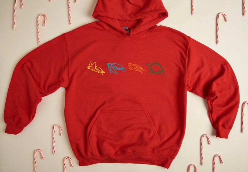 May include: Red hooded sweatshirt with a line drawing of five colorful sea turtles on the front.