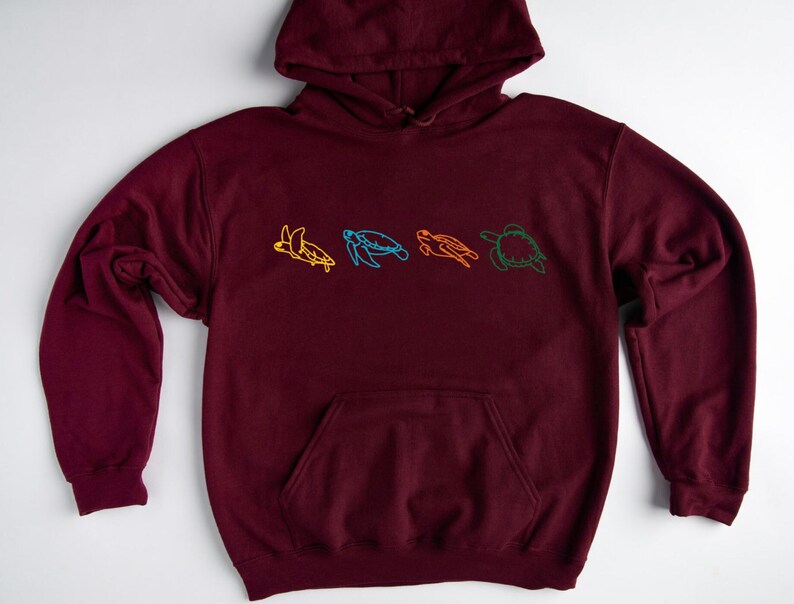 May include: A maroon hoodie with a line drawing of four sea turtles in different colors on the front.