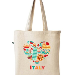 Op de afbeelding: Beige canvas draagtas met een kleurrijk hartvormig ontwerp met Italiaanse iconen, waaronder pasta, pizza en de scheve toren van Pisa. Het woord "ITALY" is gedrukt in rood, oranje en geel. De tas heeft lange hengsels.