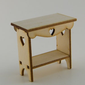 May include: A small wooden table with a shelf and heart-shaped cutouts. The table is made of light wood and has a natural finish.
