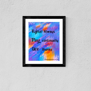 May include: A framed print with the words "Rejoice Always, Pray continually, Give thanks" in black script on a colorful abstract background of blue, orange, and purple. The text is from 1 Thessalonians 5:16-18.
