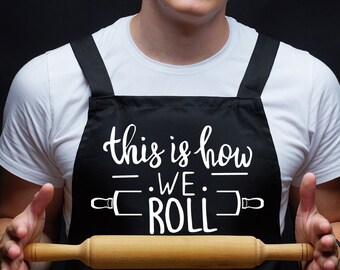 Puede incluir: Una persona que lleva un delantal negro con el texto "This is how we roll" y un rodillo delante de ella.
