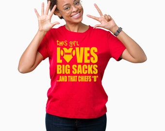 May include: Red t-shirt with a yellow graphic that says "This girl loves big sacks...and that Chiefs 'D'".