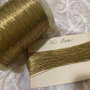 May include: A spool of gold metallic thread with a label that reads "50 Meter".