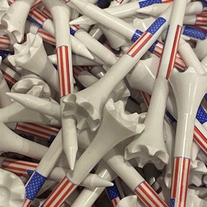May include: A pile of white golf tees with red, white, and blue American flag designs.