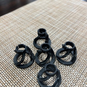 May include: Five black plastic 3D printed rings stacked on top of each other. The rings are all the same size and have a smooth finish.
