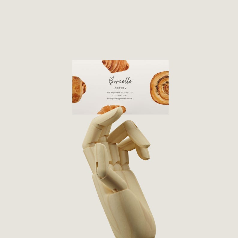 May include: A white business card with a watercolor illustration of pastries. The text on the card reads "Borcelle bakery", "123 Anywhere St., Any City", "(123) 456-7890", and "hello@mybakery.com".
