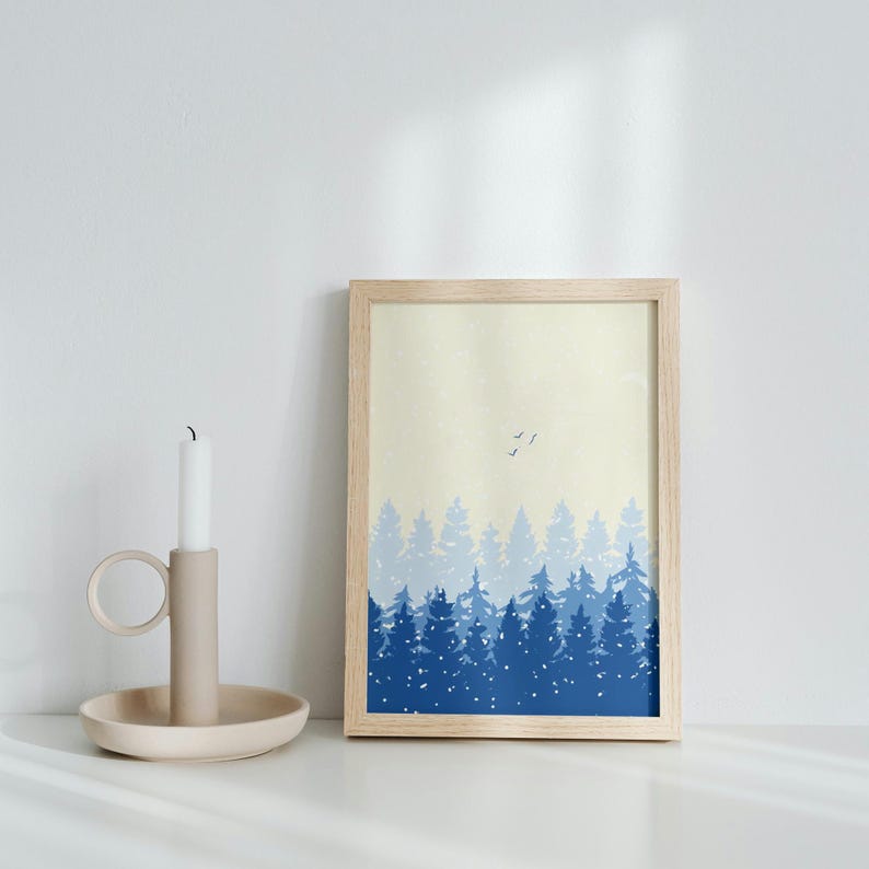 May include: A framed print of a blue and white forest scene with a light yellow background. The print features a row of trees in various shades of blue, with a few white birds flying above. The trees are silhouetted against the yellow background, creating a simple and elegant design.