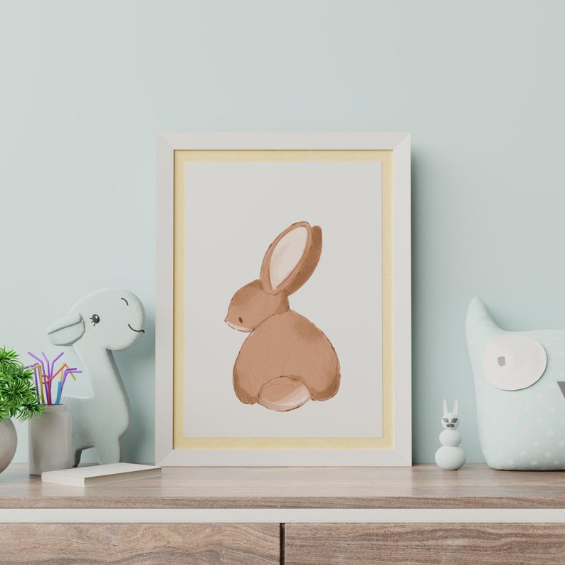 May include: A white framed print with a yellow mat featuring a watercolor illustration of a brown rabbit facing away from the viewer.