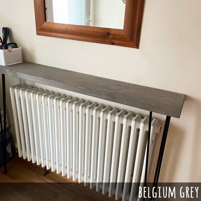 May include: A gray wooden console table with black metal legs is positioned above a white radiator. The table is painted in Belgium Grey and has a rectangular shape. A wooden framed mirror hangs on the wall above the table.
