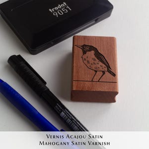 A rubber stamp with an illustration of a bird and the text EX LIBRIS CLEMENT SCARPI rests beside its stamped impression on a book page, making a parfait cadeau fait main for collectors of bijoux uniques or vintage treasures.
