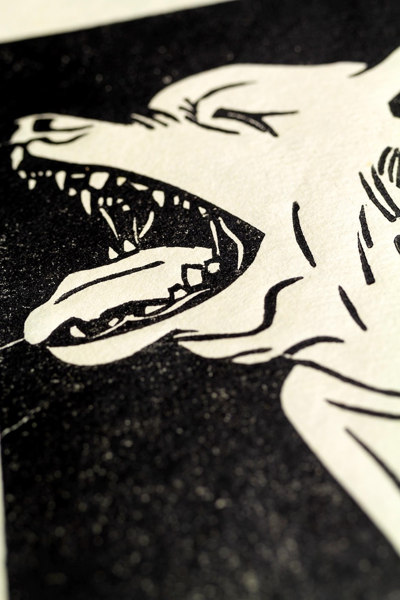 May include: Black and white illustration of a wolf's head with its mouth open, showing sharp teeth. The wolf's fur is detailed with lines and the background is black.