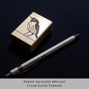 A rubber stamp with an illustration of a bird and the text EX LIBRIS CLEMENT SCARPI rests beside its stamped impression on a book page, making a parfait cadeau fait main for collectors of bijoux uniques or vintage treasures.