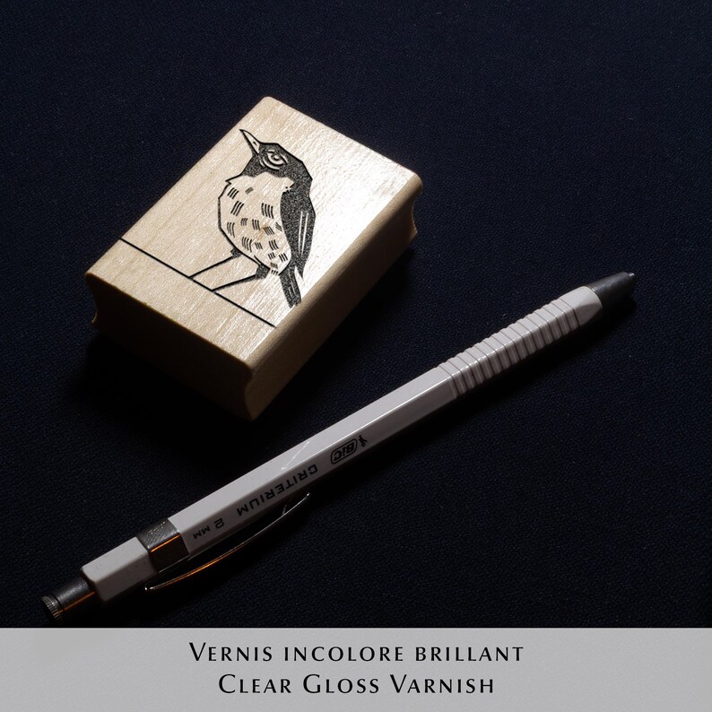 A rubber stamp with an illustration of a bird and the text EX LIBRIS CLEMENT SCARPI rests beside its stamped impression on a book page, making a parfait cadeau fait main for collectors of bijoux uniques or vintage treasures.