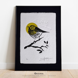 Peut inclure: Impression d'art encadrée en noir, représentant un oiseau jaune et noir perché sur une branche, sur un fond blanc texturé avec un soleil jaune. Le texte "ORIGINAL NON-CONTRACTUAL PHOTO - MOCKUP" est inclus.
