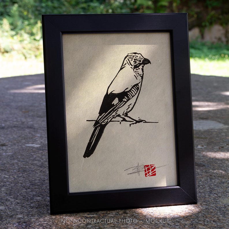 May include: A framed print with a black and white bird illustration. The artwork depicts a bird perched on a branch, set against a light background, and is enclosed in a black frame. A red square stamp is in the lower right corner.