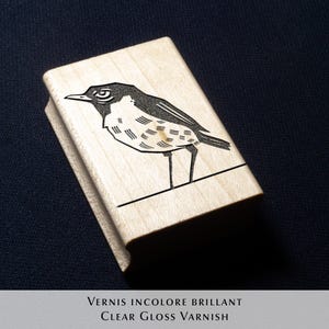 A rubber stamp with an illustration of a bird and the text EX LIBRIS CLEMENT SCARPI rests beside its stamped impression on a book page, making a parfait cadeau fait main for collectors of bijoux uniques or vintage treasures.