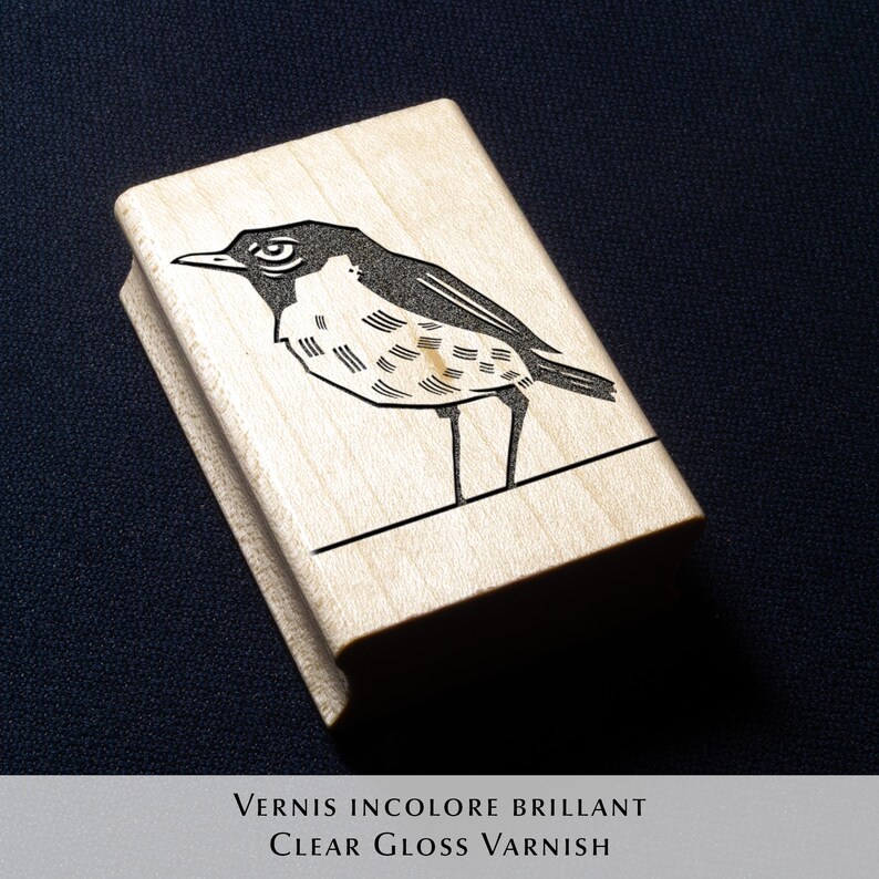 A rubber stamp with an illustration of a bird and the text EX LIBRIS CLEMENT SCARPI rests beside its stamped impression on a book page, making a parfait cadeau fait main for collectors of bijoux uniques or vintage treasures.