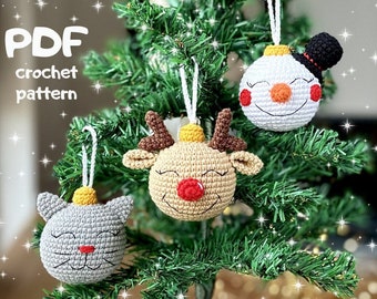 May include: Three crocheted Christmas ornaments hanging on a green Christmas tree. The ornaments are a snowman, a reindeer, and a cat. The ornaments are all white with red and black details. The ornaments are all about 3 inches in diameter. PDF crochet pattern.
