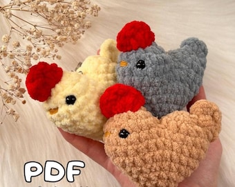 May include: Three crocheted chicken amigurumi toys. The chickens are in yellow, gray, and brown. Each chicken has a red pom-pom for a comb and black eyes. The text "PDF crochet pattern" is at the bottom of the image.